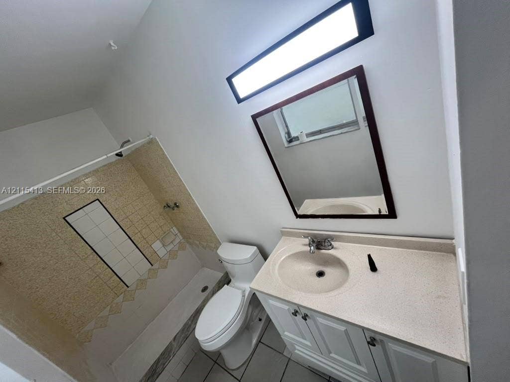 3001 NW 4th Terrace, #173, Pompano Beach, Pompano Beach, FL 33064 Bathroom featuring a vanity with a stone-finish countertop, undermount sink, tiled tub-shower surround, rectangular wall-mounted mirror, and linear light fixture