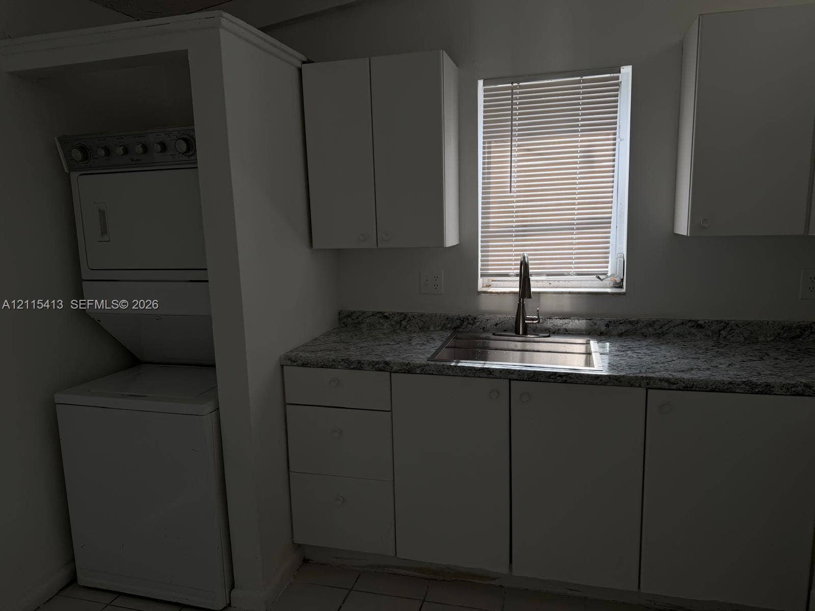 3001 NW 4th Terrace, #173, Pompano Beach, Pompano Beach, FL 33064 Utility space featuring white cabinetry, stone-finish countertops, stainless steel sink with a high-arch faucet, and an integrated stacked laundry unit