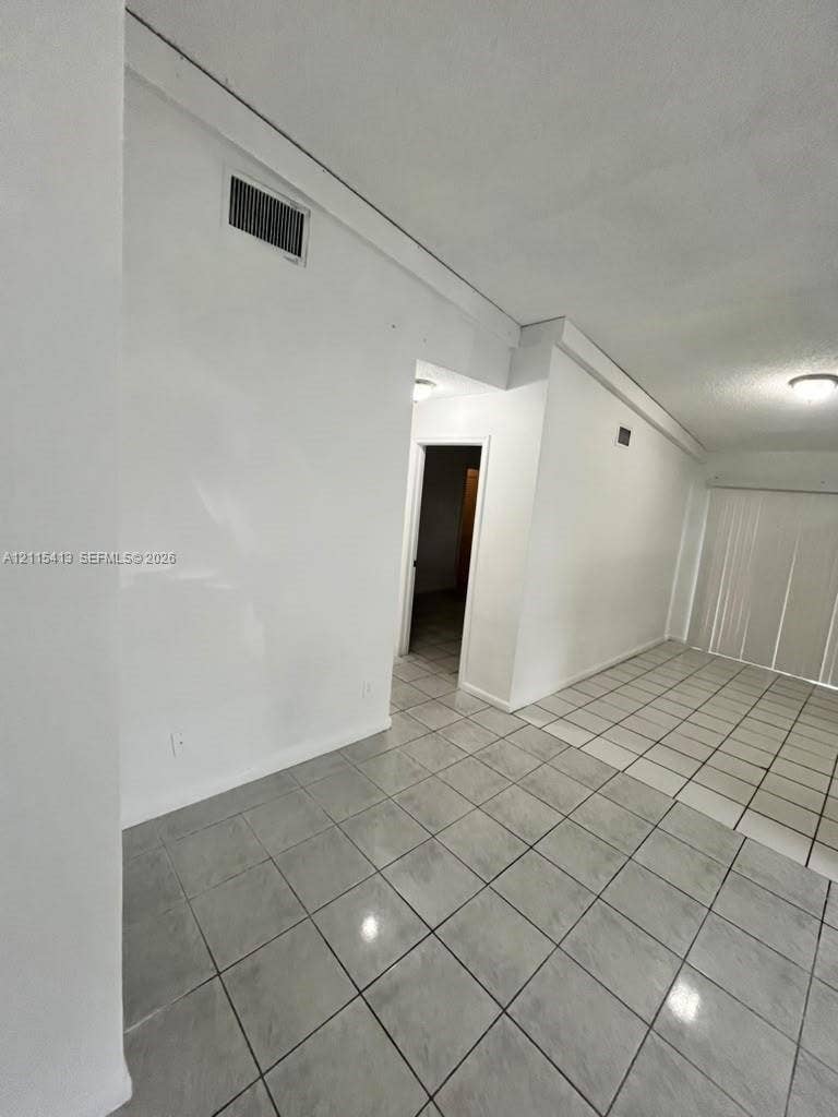 3001 NW 4th Terrace, #173, Pompano Beach, Pompano Beach, FL 33064 Interior space featuring light gray square tile flooring and white wall finishes, accented by ceiling-mounted lighting fixtures