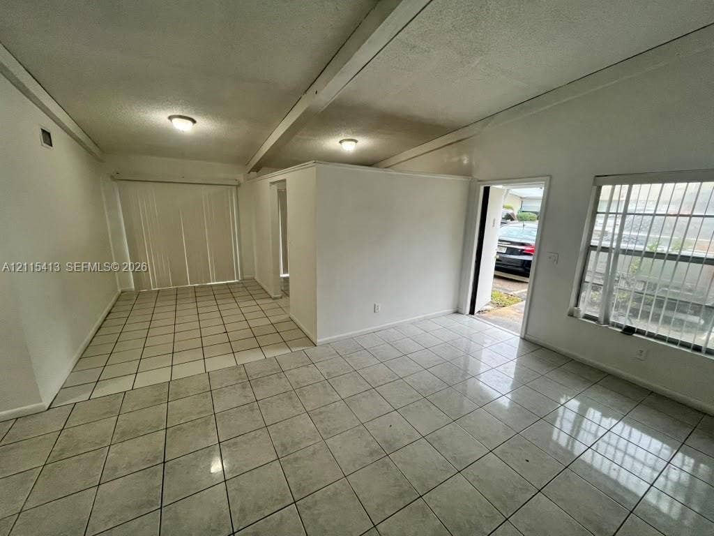 3001 NW 4th Terrace, #173, Pompano Beach, Pompano Beach, FL 33064 Interior space featuring light-colored ceramic tile flooring, vaulted ceilings with exposed beams, recessed lighting, and vertical window blinds