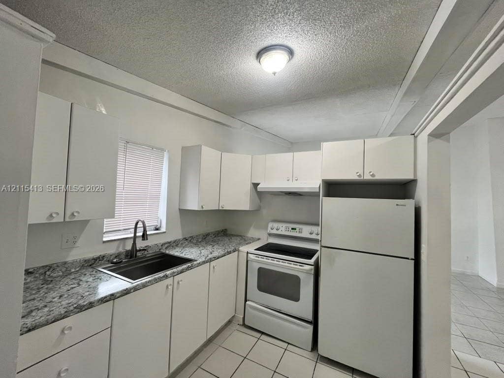 3001 NW 4th Terrace, #173, Pompano Beach, Pompano Beach, FL 33064 Kitchen featuring white cabinetry, stone-finish countertops, tile flooring, and integrated white appliances