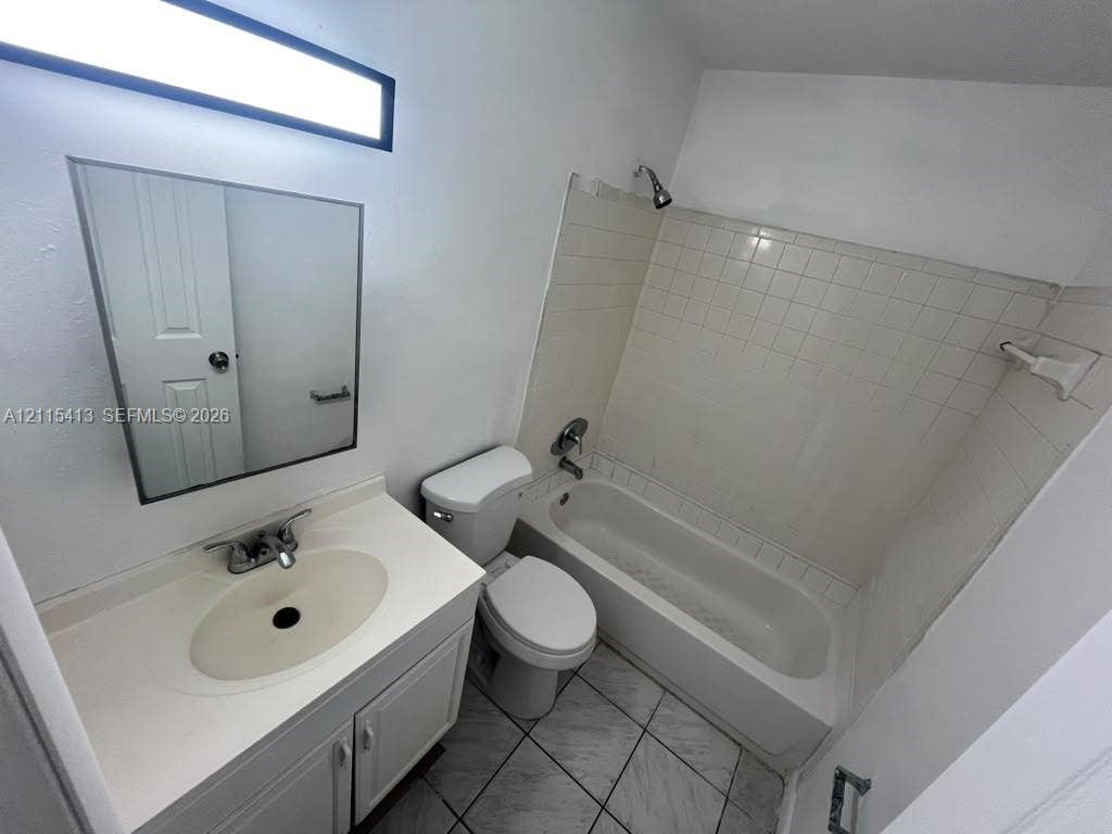 3001 NW 4th Terrace, #173, Pompano Beach, Pompano Beach, FL 33064 Bathroom featuring a vanity with an integrated sink, rectangular wall-mounted mirror, ceramic tile flooring, and a tub-shower combination with tiled surround