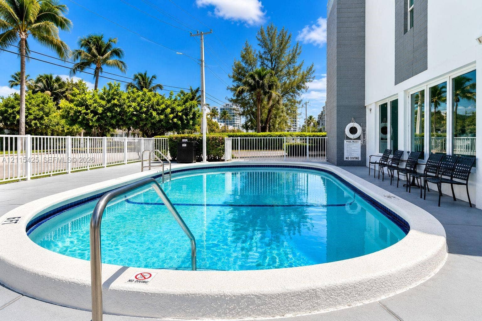 550 Bayshore Drive, #404, Fort Lauderdale, FL 33304 Oval swimming pool featuring a concrete deck, metal safety fencing, and stainless steel handrails