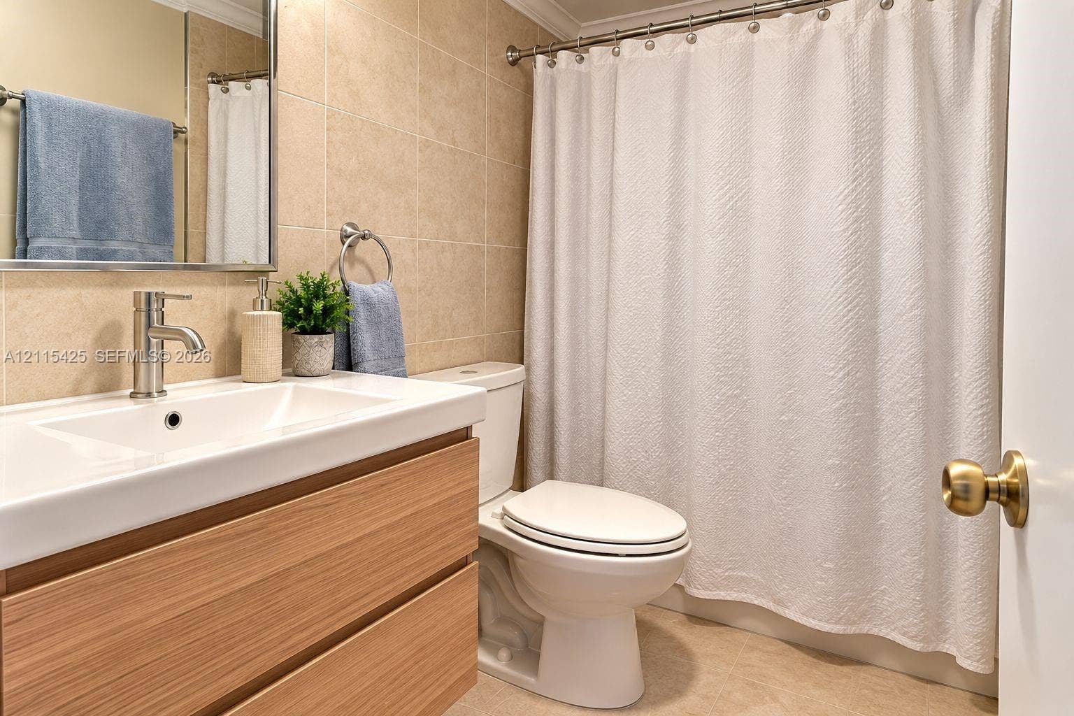 550 Bayshore Drive, #404, Fort Lauderdale, FL 33304 Bathroom featuring a wood-finish floating vanity with a rectangular integrated sink, brushed nickel faucet, large wall-mounted mirror, and neutral-toned wall tiling