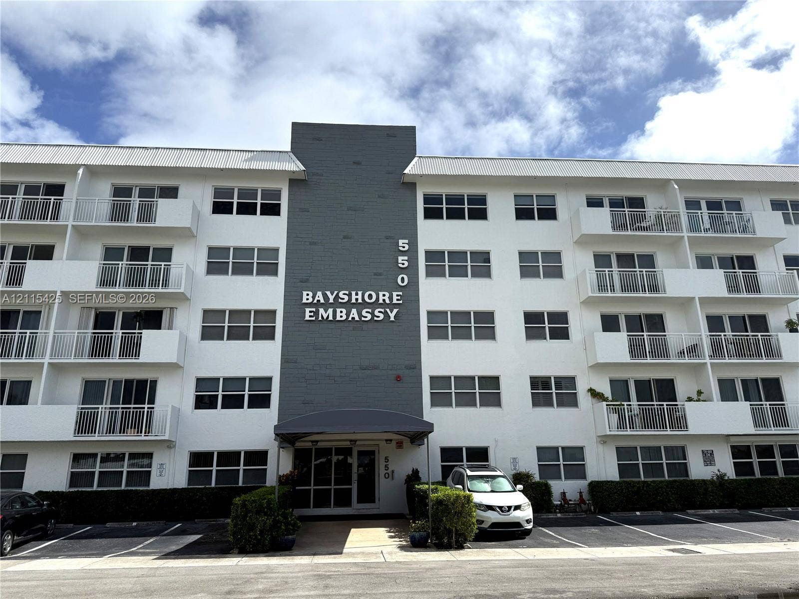 550 Bayshore Drive, #404, Fort Lauderdale, FL 33304 Multi-story building exterior featuring a stone-accented facade, private balconies with metal railings, and ground-level paved parking