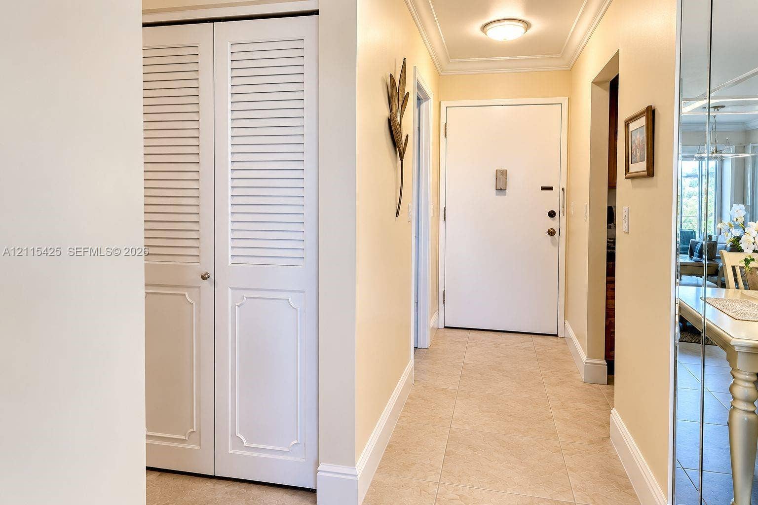 550 Bayshore Drive, #404, Fort Lauderdale, FL 33304 Entryway featuring light-toned tile flooring, white louvered-style closet doors, crown molding, and a flush-mount ceiling light fixture