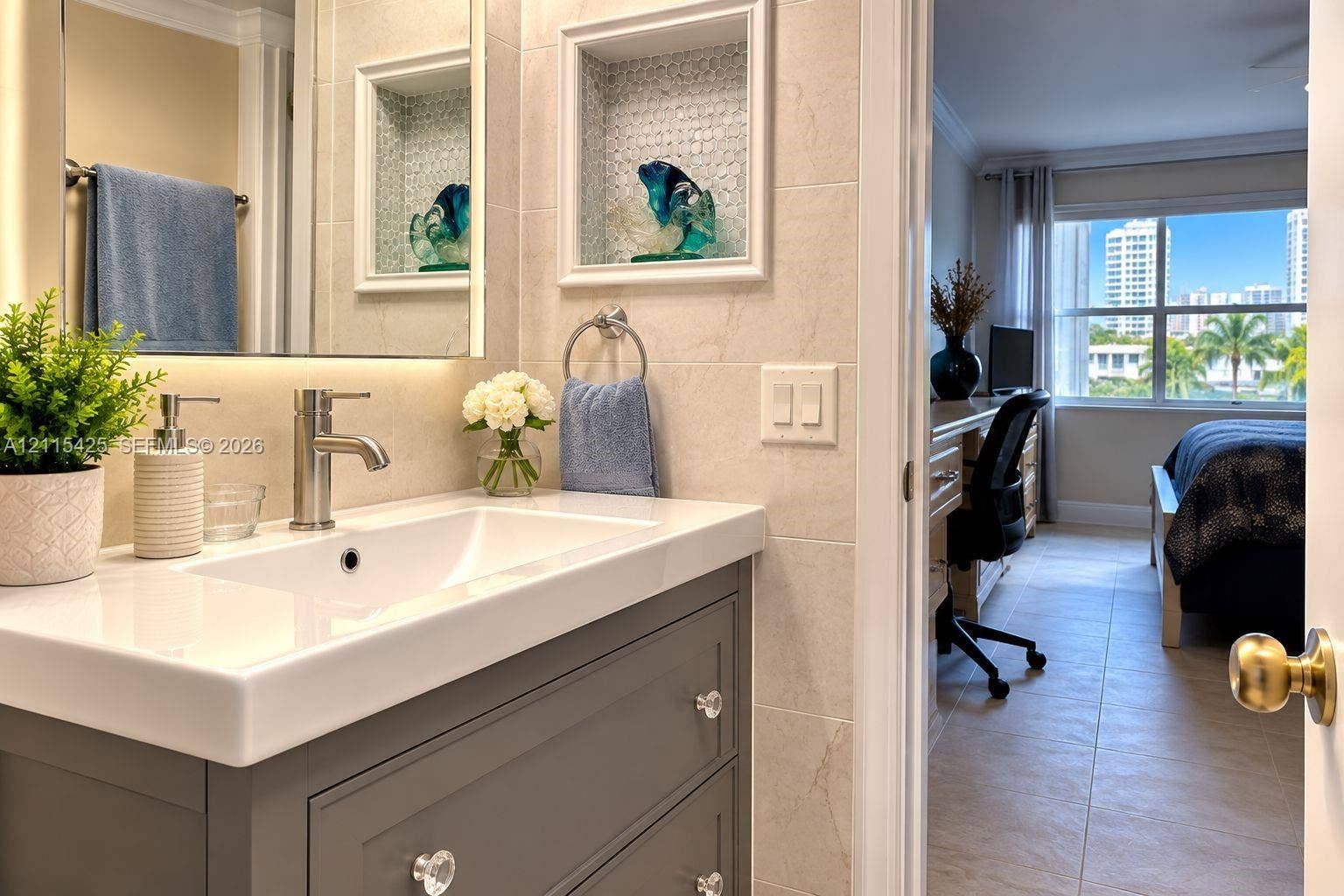 550 Bayshore Drive, #404, Fort Lauderdale, FL 33304 Vanity featuring a rectangular basin, quartz countertop, and grey cabinetry with crystal-style hardware, accompanied by a recessed wall niche with tiled backsplash