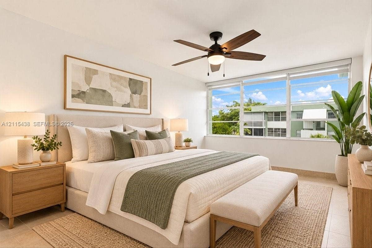 Neutral-toned interior featuring large-format tile flooring, oversized horizontal window with exterior scenery, and a central ceiling fan with integrated light fixture