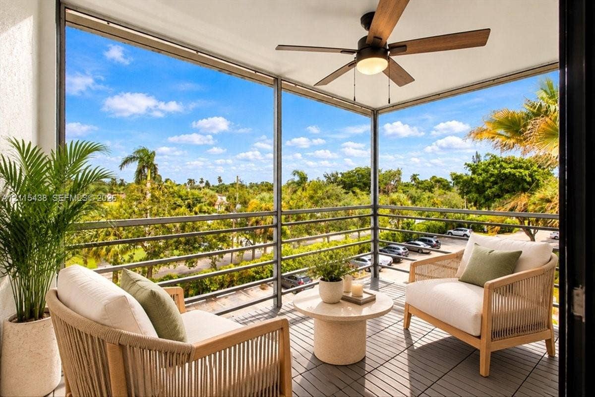 Covered balcony featuring screened enclosure, integrated ceiling fan with light fixture, and horizontal metal railing
