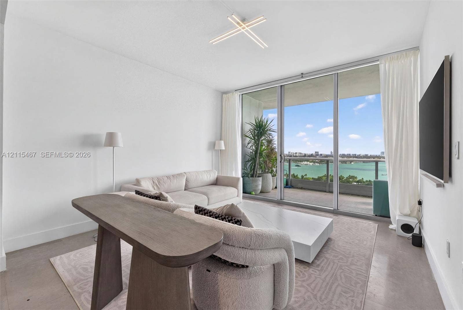 900 Biscayne Boulevard, #2104, Miami, FL 33132 Floor-to-ceiling glass sliding doors, concrete flooring, modern geometric LED ceiling fixture, and covered outdoor balcony