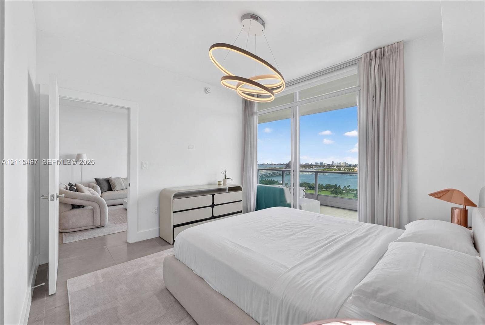 900 Biscayne Boulevard, #2104, Miami, FL 33132 Floor-to-ceiling windows, sculptural multi-ring light fixture, wood-finish flooring, and private balcony with water scenery