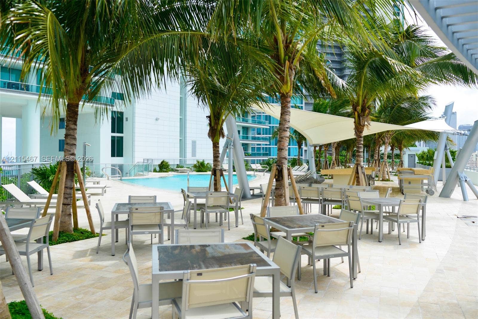 900 Biscayne Boulevard, #2104, Miami, FL 33132 Outdoor terrace featuring natural stone paving, an inground swimming pool, integrated shade structures, and mature palm trees