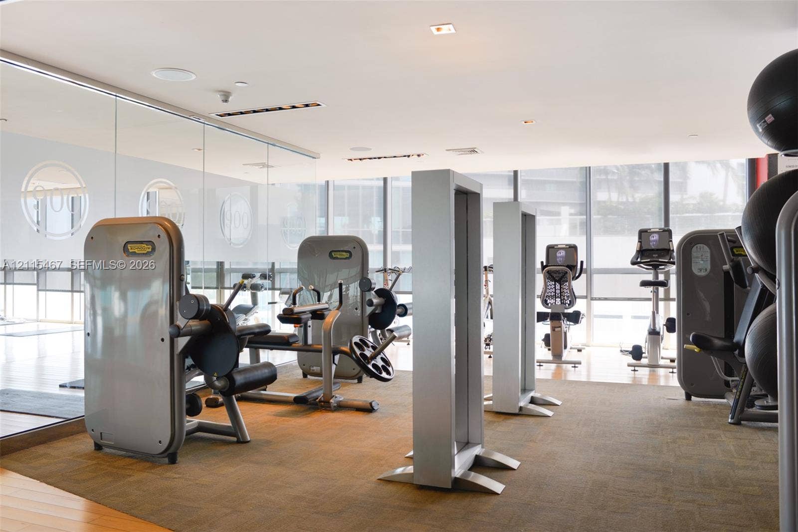 900 Biscayne Boulevard, #2104, Miami, FL 33132 Fitness facility featuring floor-to-ceiling glass windows, recessed ceiling lighting, large-scale wall mirrors, and integrated sound system speakers