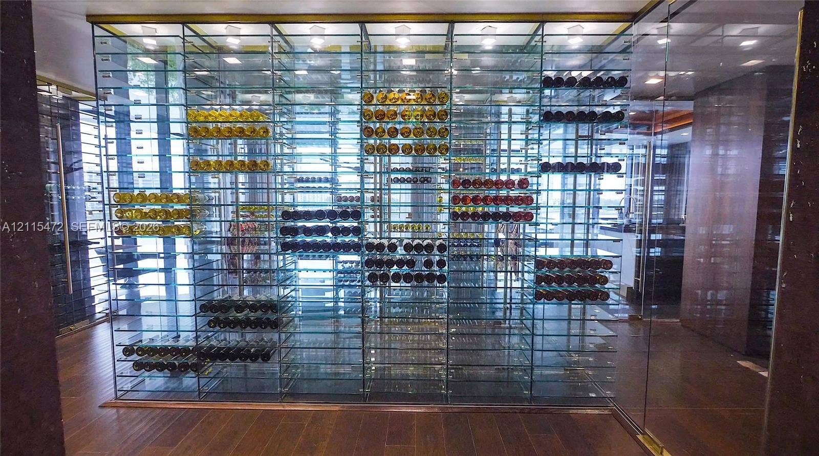 Temperature-controlled wine display featuring floor-to-ceiling glass paneling, metal racking, integrated recessed lighting, and wood-finish flooring