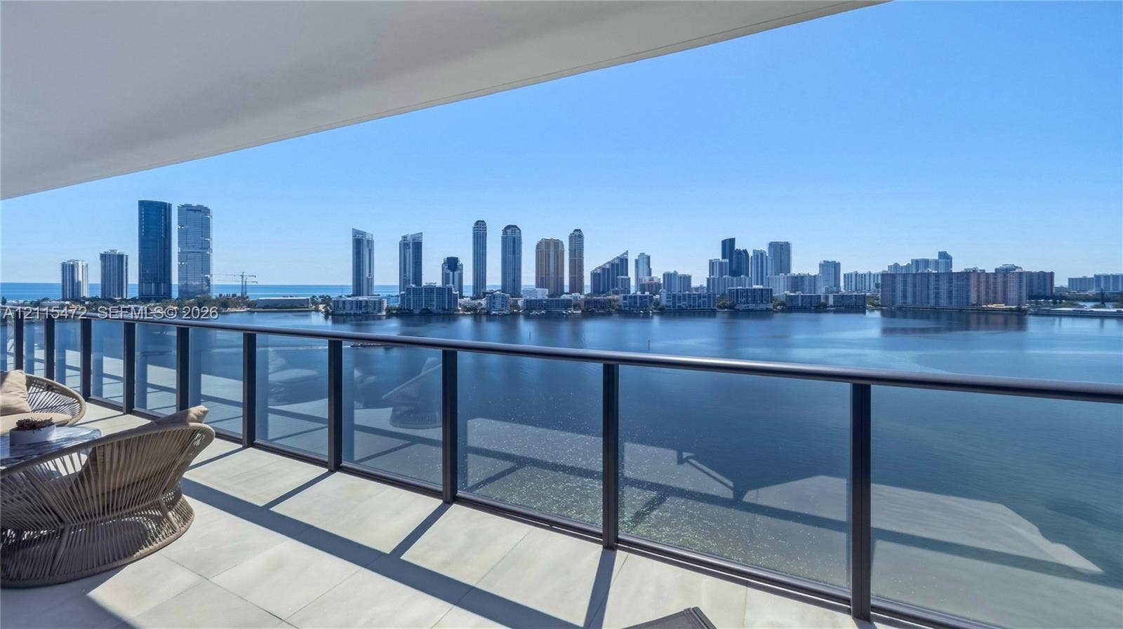 Covered terrace featuring light-toned tile flooring and a glass-paneled railing with a metal frame