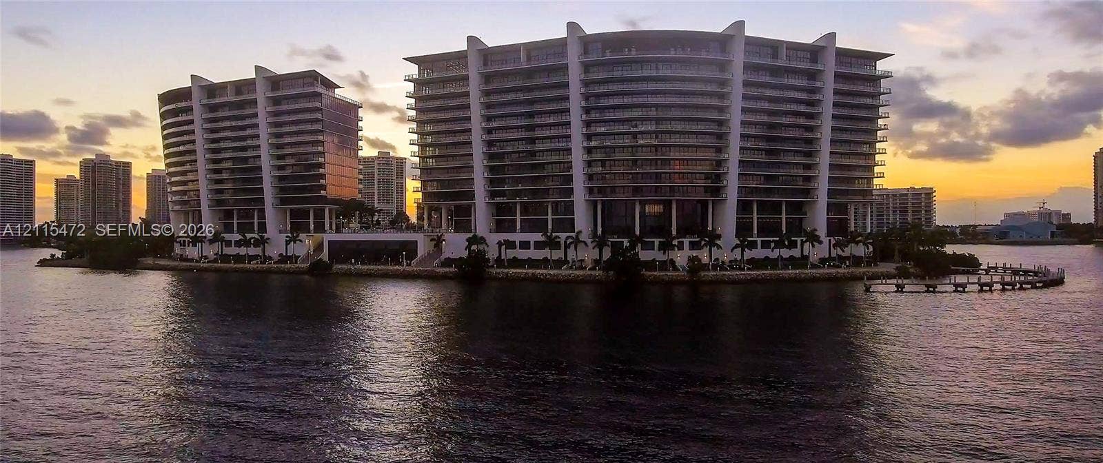 Waterfront high-rise complex featuring curvilinear architecture, tiered balconies, floor-to-ceiling glass paneling, and private maritime dockage