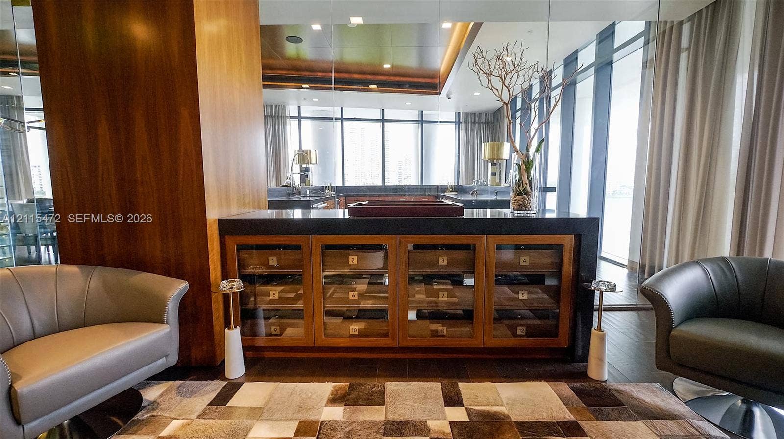 Built-in storage cabinet with glass-front drawers, dark stone countertop, floor-to-ceiling windows, wood-finish wall paneling, and recessed ceiling lighting