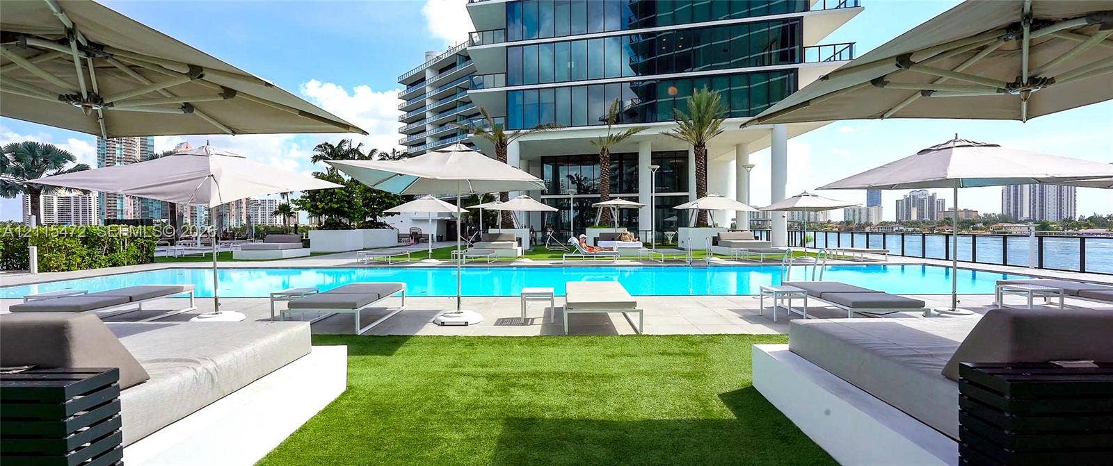 Outdoor swimming pool featuring a paved deck, artificial turf, and a black metal perimeter railing