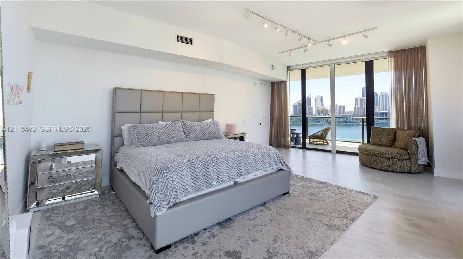 Floor-to-ceiling windows, wood-finish flooring, adjustable track lighting, and a private balcony