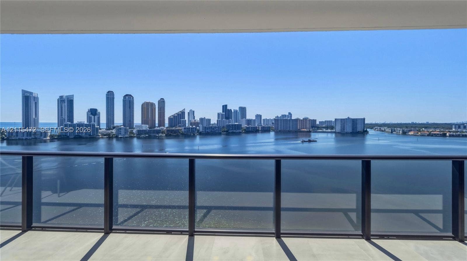 Covered balcony featuring sleek dark metal railings and tile flooring, showcasing water and cityscape scenery