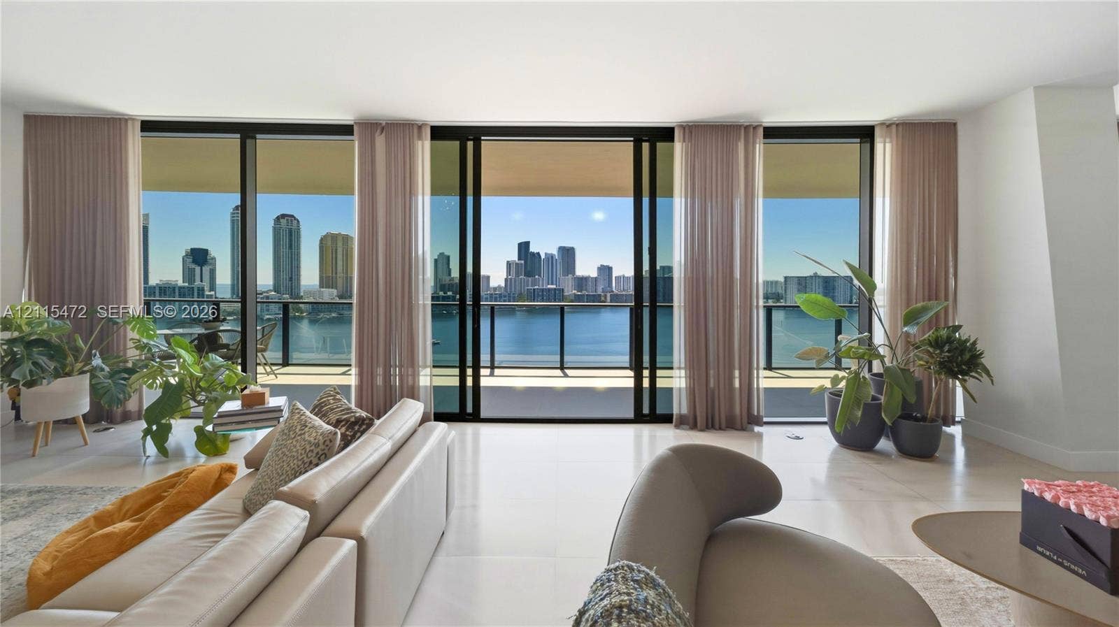 Floor-to-ceiling sliding glass walls, expansive private balcony, polished tile flooring, and urban waterfront panorama
