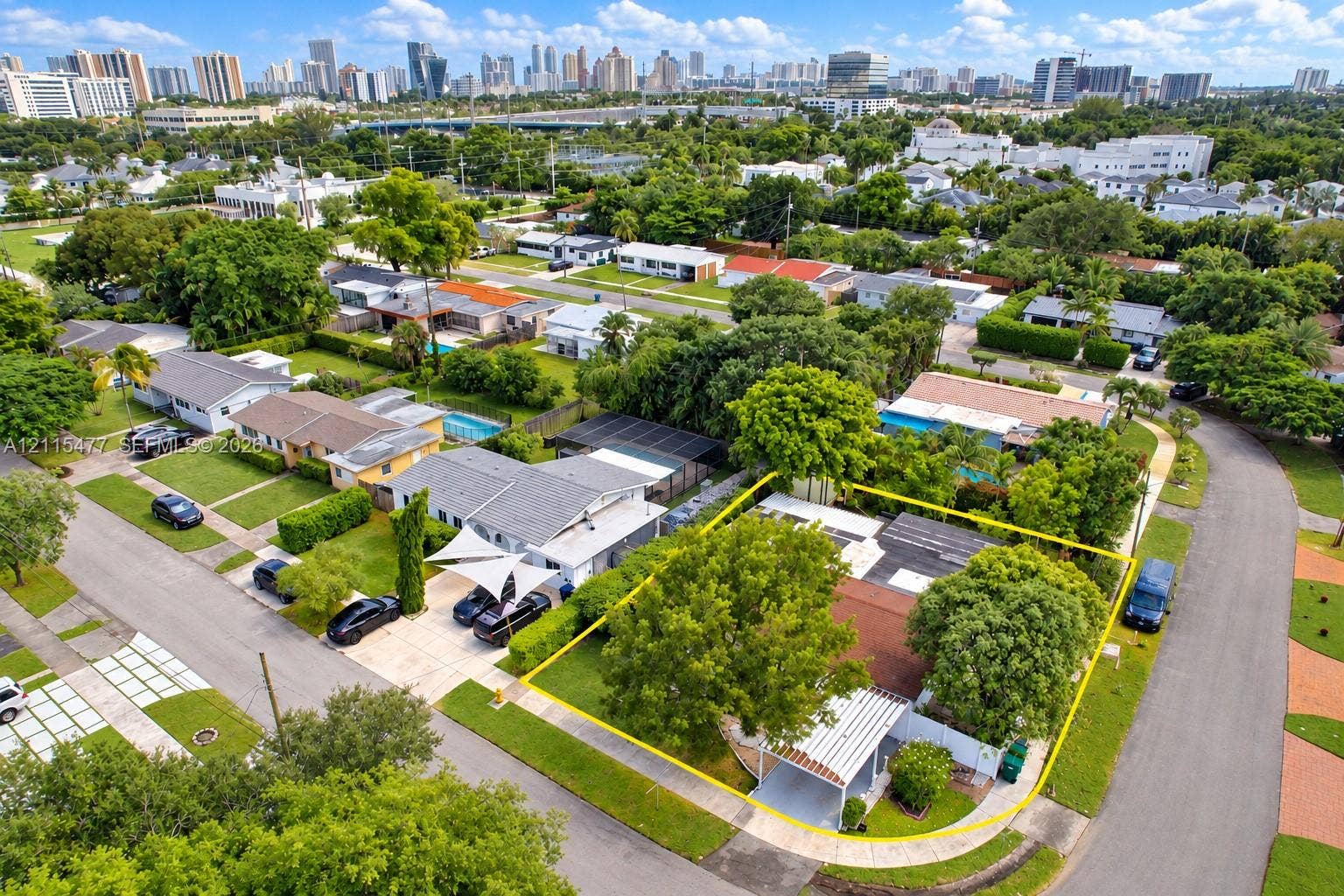 2510 NE 208th Terrace, Miami, FL 33180 Aerial perspective featuring a corner lot property with a covered carport, mature shade trees, and perimeter fencing