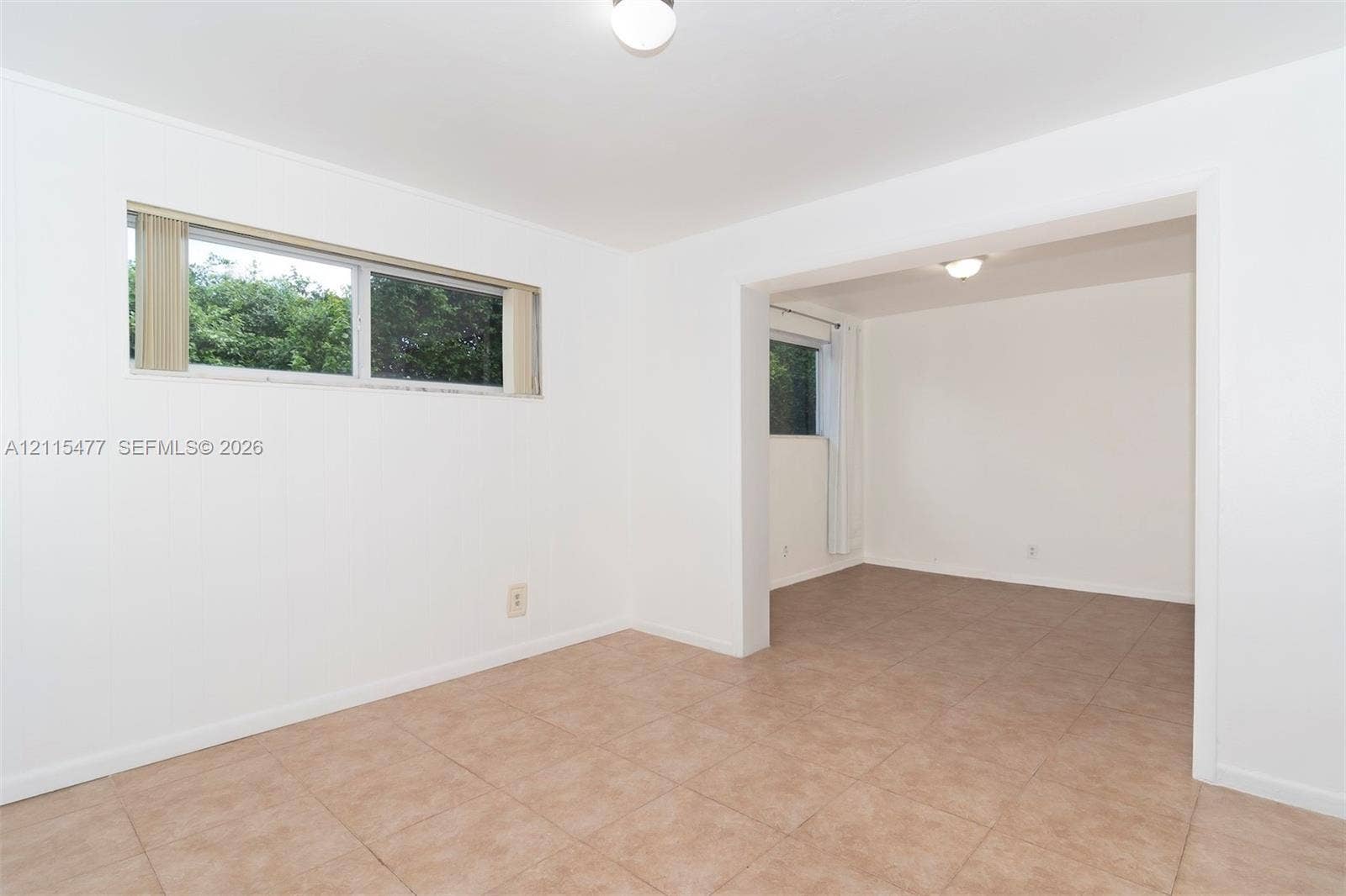 2510 NE 208th Terrace, Miami, FL 33180 Interior space featuring neutral wall tones, large-format tile flooring, and horizontally oriented windows with natural light exposure