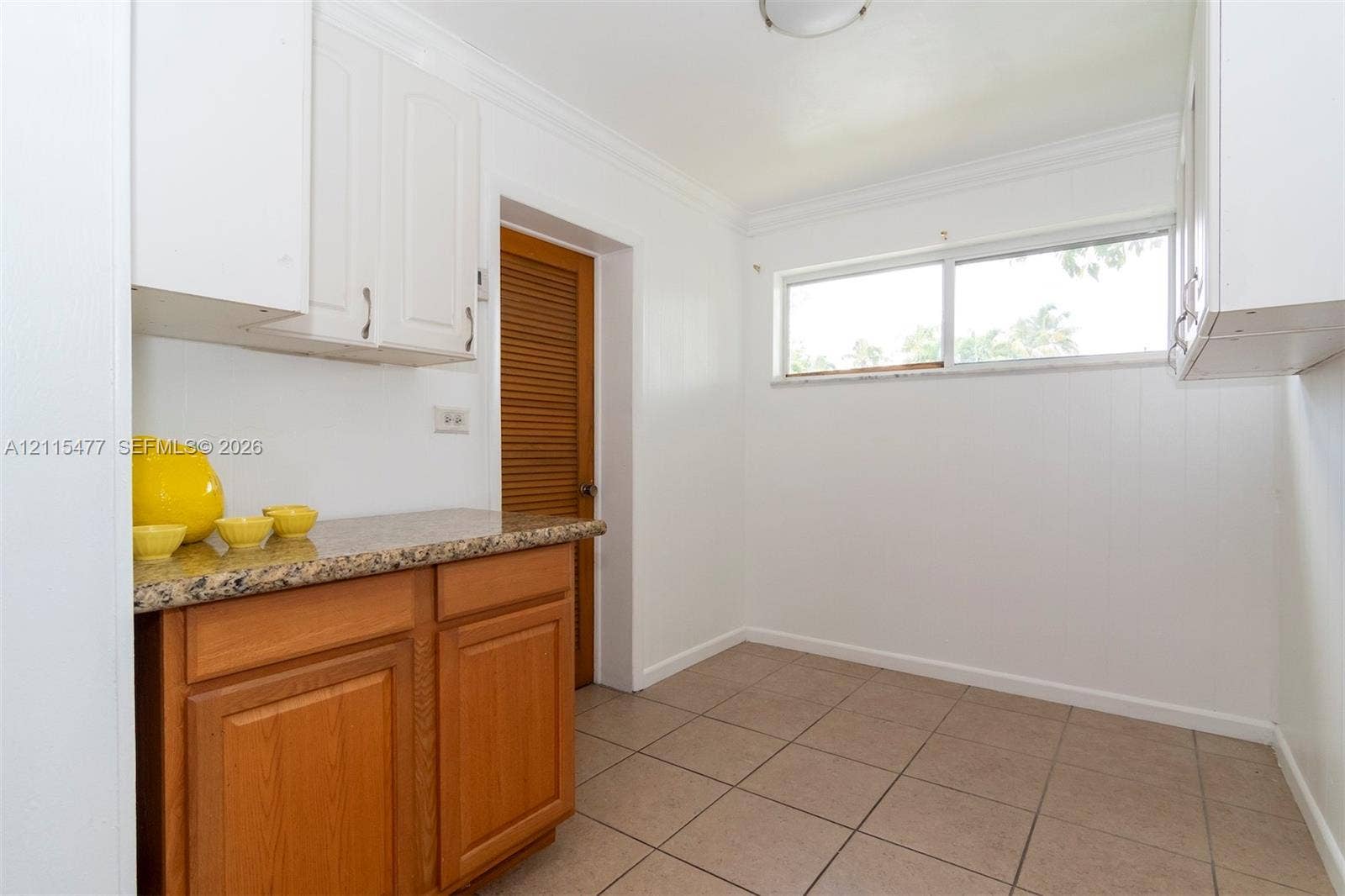 2510 NE 208th Terrace, Miami, FL 33180 Kitchen area featuring light-toned cabinetry, stone-finish countertops, horizontal window, tile flooring, and louvered wood-finish door