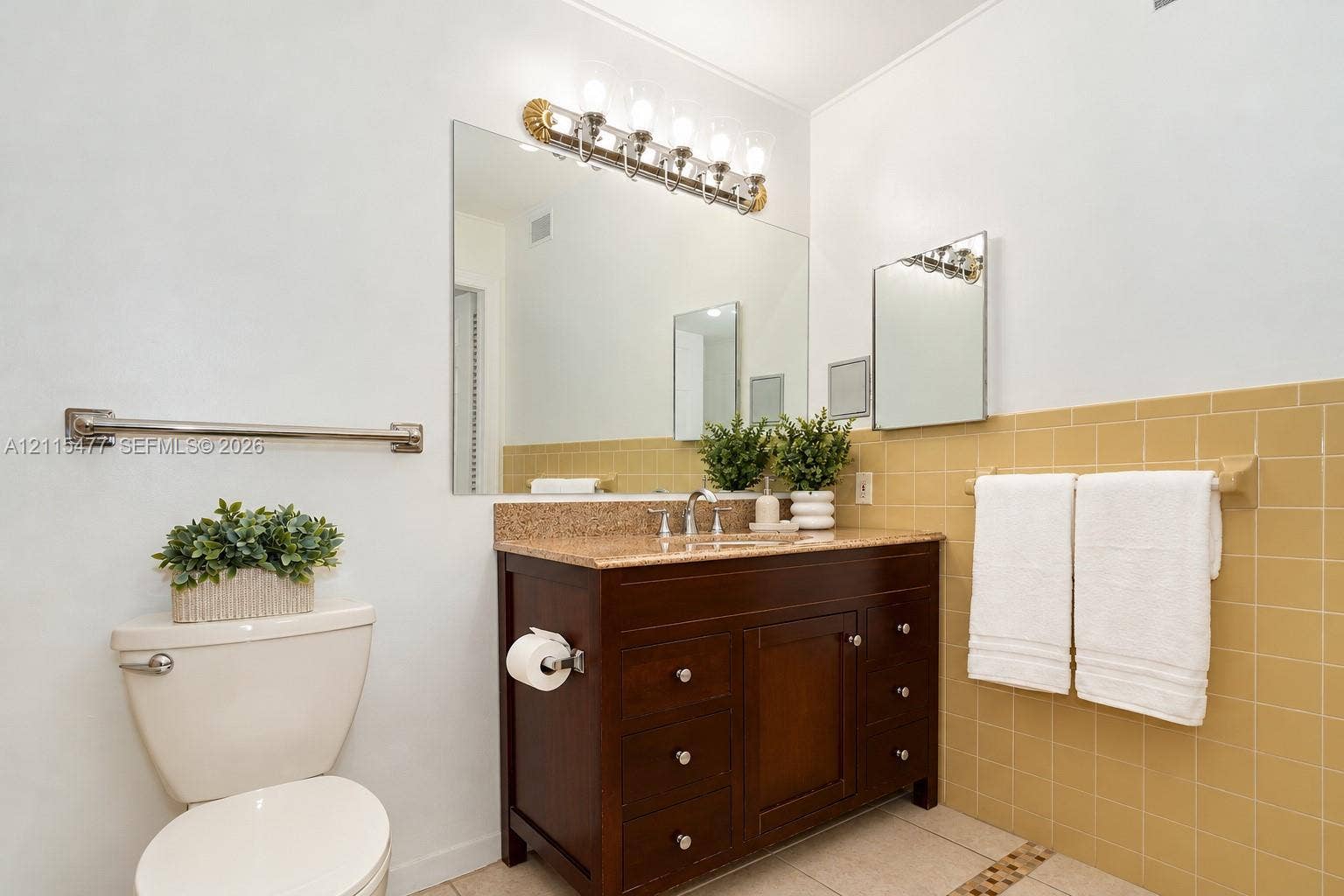 2510 NE 208th Terrace, Miami, FL 33180 Bathroom featuring a dark wood-finish vanity, stone-surfaced countertop with an integrated basin, wall-to-wall mirror, multi-light fixture, and ceramic tile wall accents