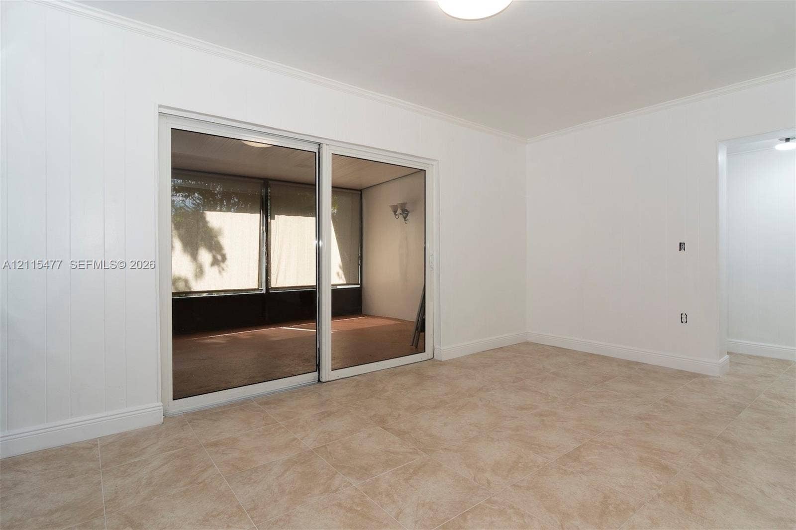2510 NE 208th Terrace, Miami, FL 33180 Interior space featuring large-format ceramic tile flooring, vertical paneling, and a dual-panel sliding glass door