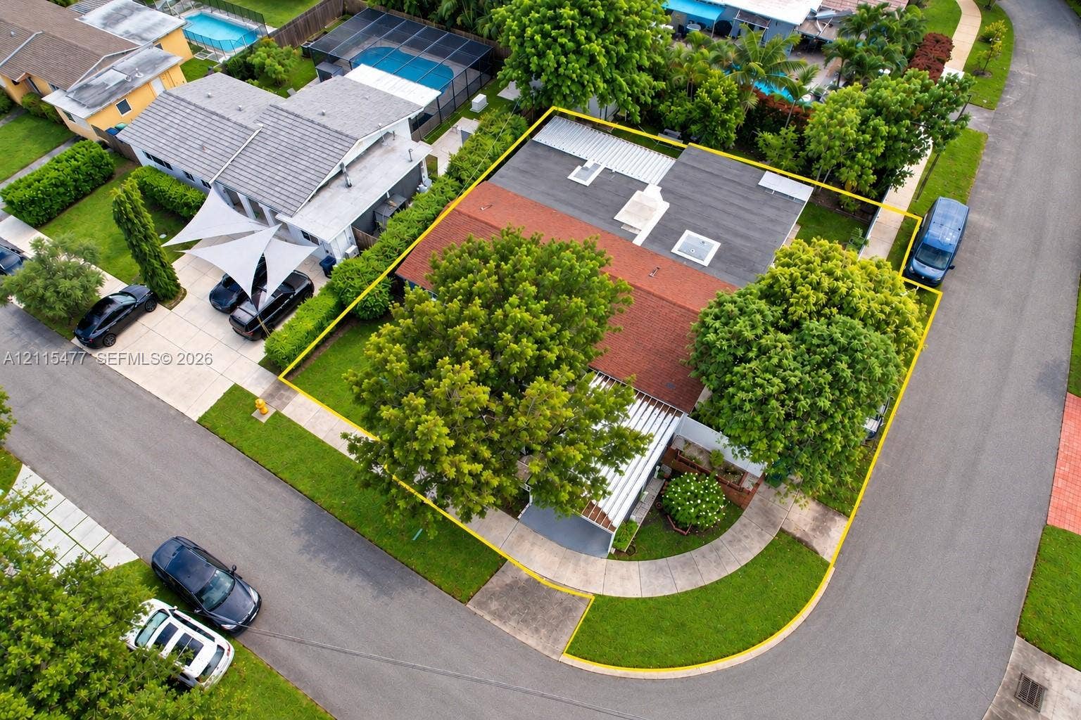 2510 NE 208th Terrace, Miami, FL 33180 Corner lot featuring a multi-section roofline with skylights, a paved driveway, and mature landscaping