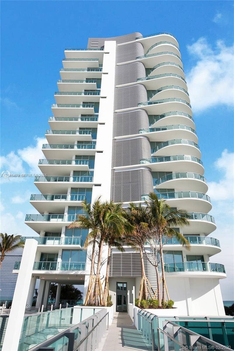Modern high-rise residential tower featuring curvilinear balconies, glass railings, floor-to-ceiling windows, and a structured facade