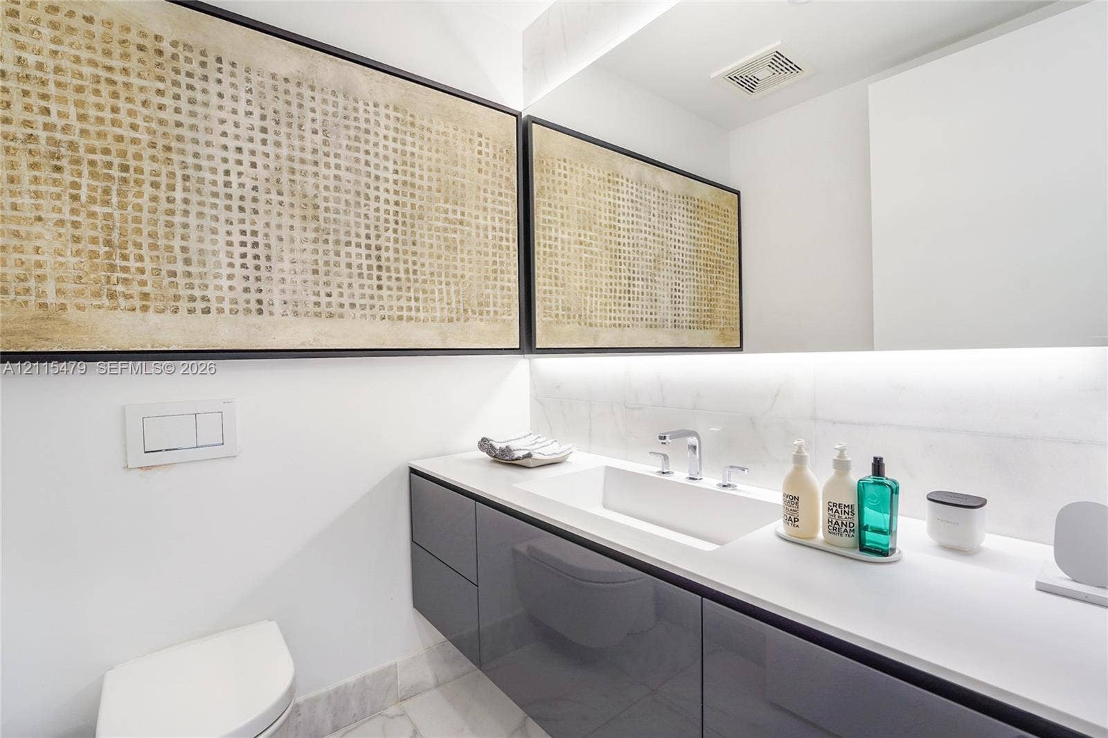 Floating vanity featuring high-gloss cabinetry, integrated sink, stone-finish countertop, and polished chrome widespread faucet