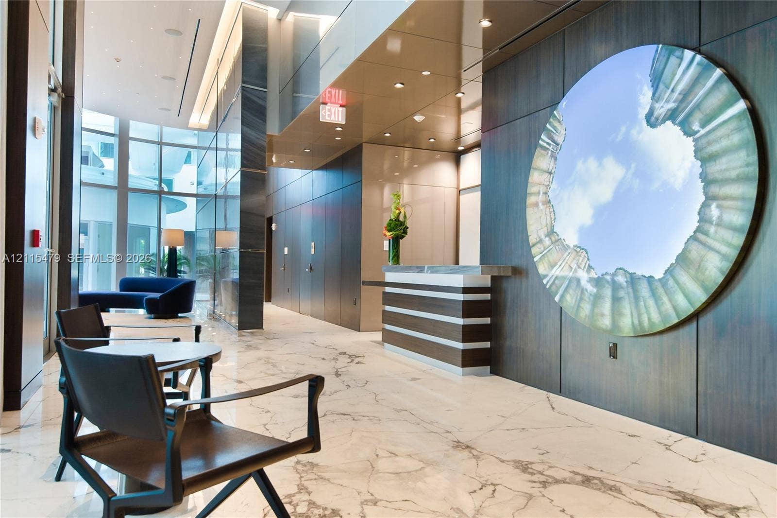 Lobby area featuring large-format stone flooring, floor-to-ceiling glass windows, recessed ceiling lighting, and dark wood-finish wall paneling