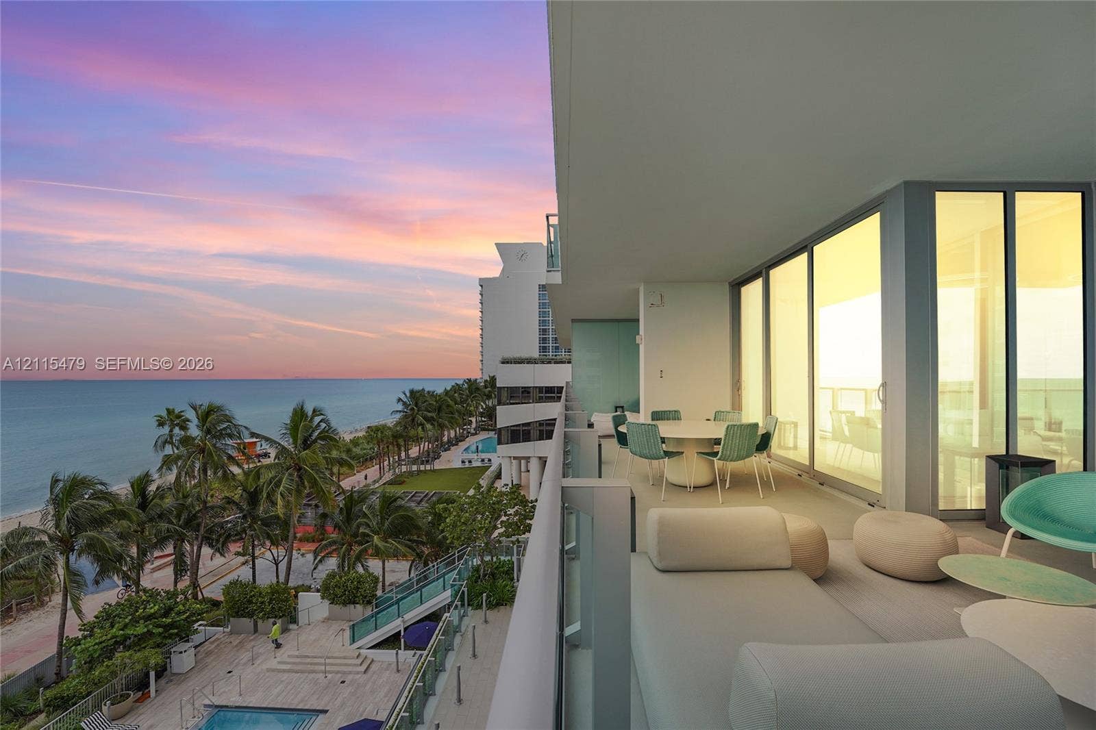 Expansive covered terrace featuring glass panel railings, floor-to-ceiling sliding glass doors, and panoramic ocean and coastline scenery