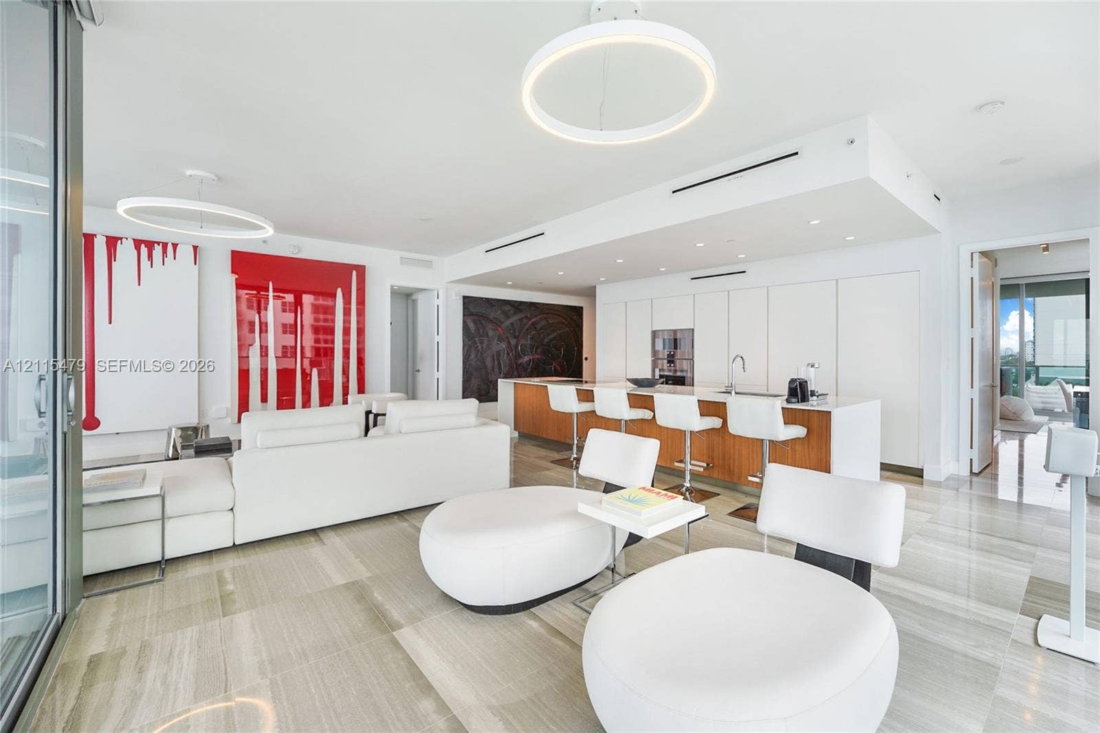 Open-concept interior featuring large-format tile flooring, modern circular pendant lighting, and flat-panel cabinetry