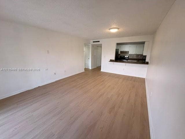 9301 SW 92nd Avenue, #A418, Miami, Miami, FL 33176 Open-concept interior featuring light wood-finish flooring, a pass-through kitchen opening, flush-mount ceiling lighting, and solid-core interior doors