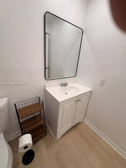 9301 SW 92nd Avenue, #A418, Miami, Miami, FL 33176 White vanity cabinet with an integrated white countertop, rounded sink basin, black-framed wall mirror, and light wood-finish flooring