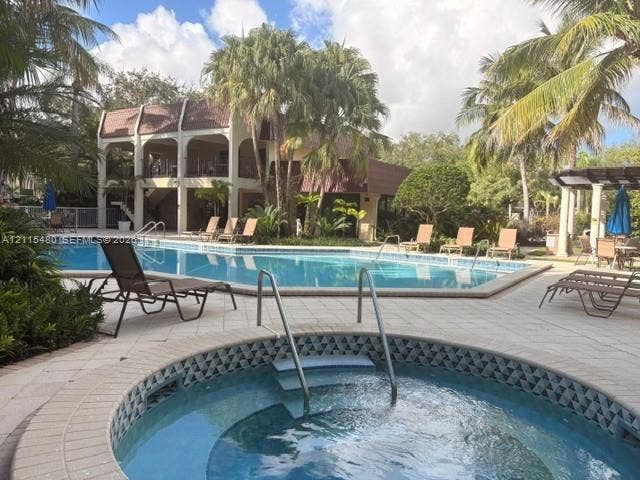 9301 SW 92nd Avenue, #A418, Miami, Miami, FL 33176 In-ground swimming pool and circular spa featuring tile accents, surrounded by a paved deck and mature palm trees