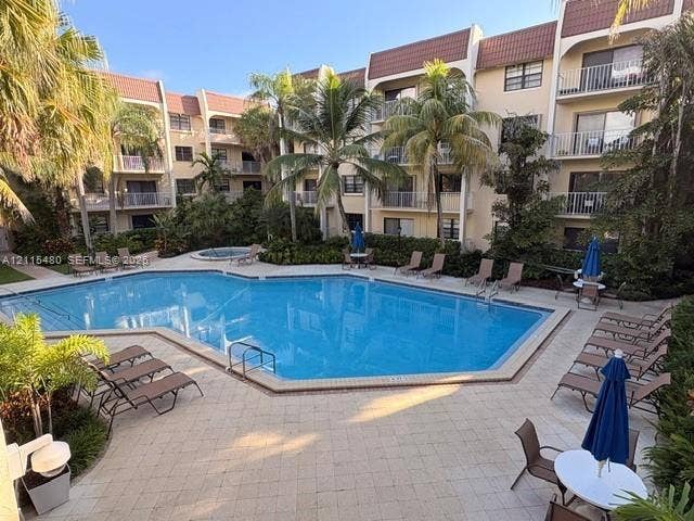 9301 SW 92nd Avenue, #A418, Miami, Miami, FL 33176 Community swimming pool and hot tub set within a paver-stone deck, surrounded by mature palm trees and multi-story residential building with private balconies