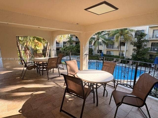 9301 SW 92nd Avenue, #A418, Miami, Miami, FL 33176 Covered balcony featuring tile flooring, arched architectural supports, and decorative metal railings overlooking a swimming pool
