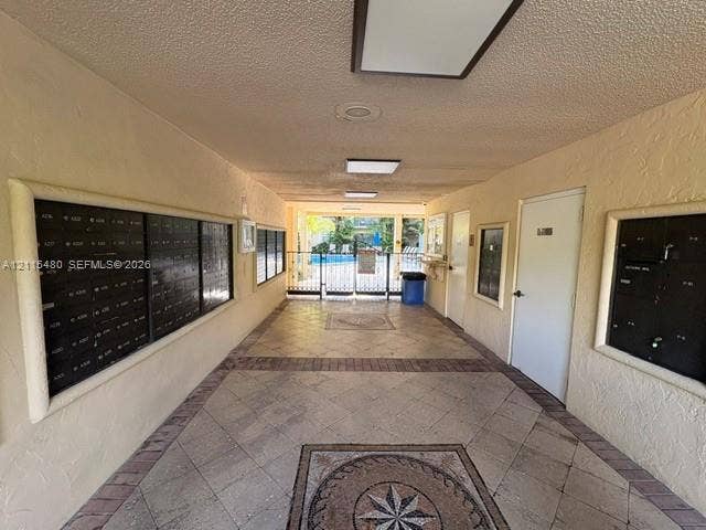 9301 SW 92nd Avenue, #A418, Miami, Miami, FL 33176 Covered mail station featuring multi-unit metal lockboxes, tile flooring with intricate central inlay, recessed lighting, and a gated entrance
