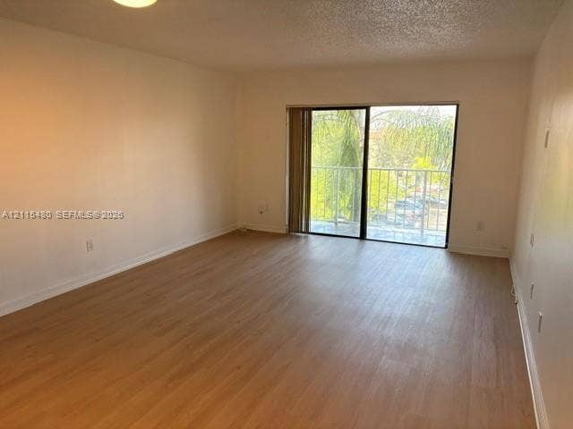 9301 SW 92nd Avenue, #A418, Miami, Miami, FL 33176 Living area featuring wood-finish flooring, ceiling lighting, and sliding glass doors with access to an exterior balcony