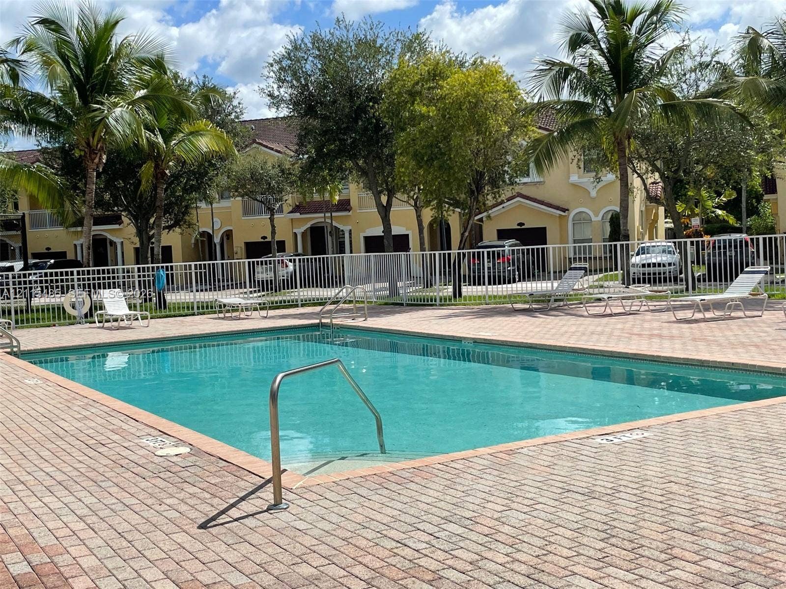 14973 SW 9th Terrace, Miami, Miami, FL 33194 Swimming pool featuring a brick-paver deck, metal perimeter fencing, and stainless steel handrails