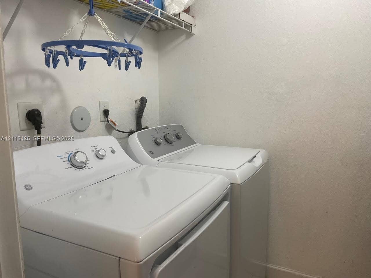 14973 SW 9th Terrace, Miami, Miami, FL 33194 Laundry area featuring white washer and dryer units with integrated dial controls and overhead wire shelving