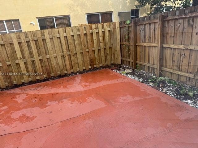 14973 SW 9th Terrace, Miami, Miami, FL 33194 Rear courtyard featuring a terra-cotta finished concrete patio, enclosed by a full-height wood picket fence with integrated gravel landscaping beds