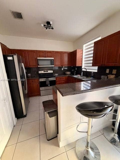 14973 SW 9th Terrace, Miami, Miami, FL 33194 Kitchen featuring wood cabinetry, stone-surface countertops, stainless steel appliances, ceramic tile flooring, and a breakfast bar