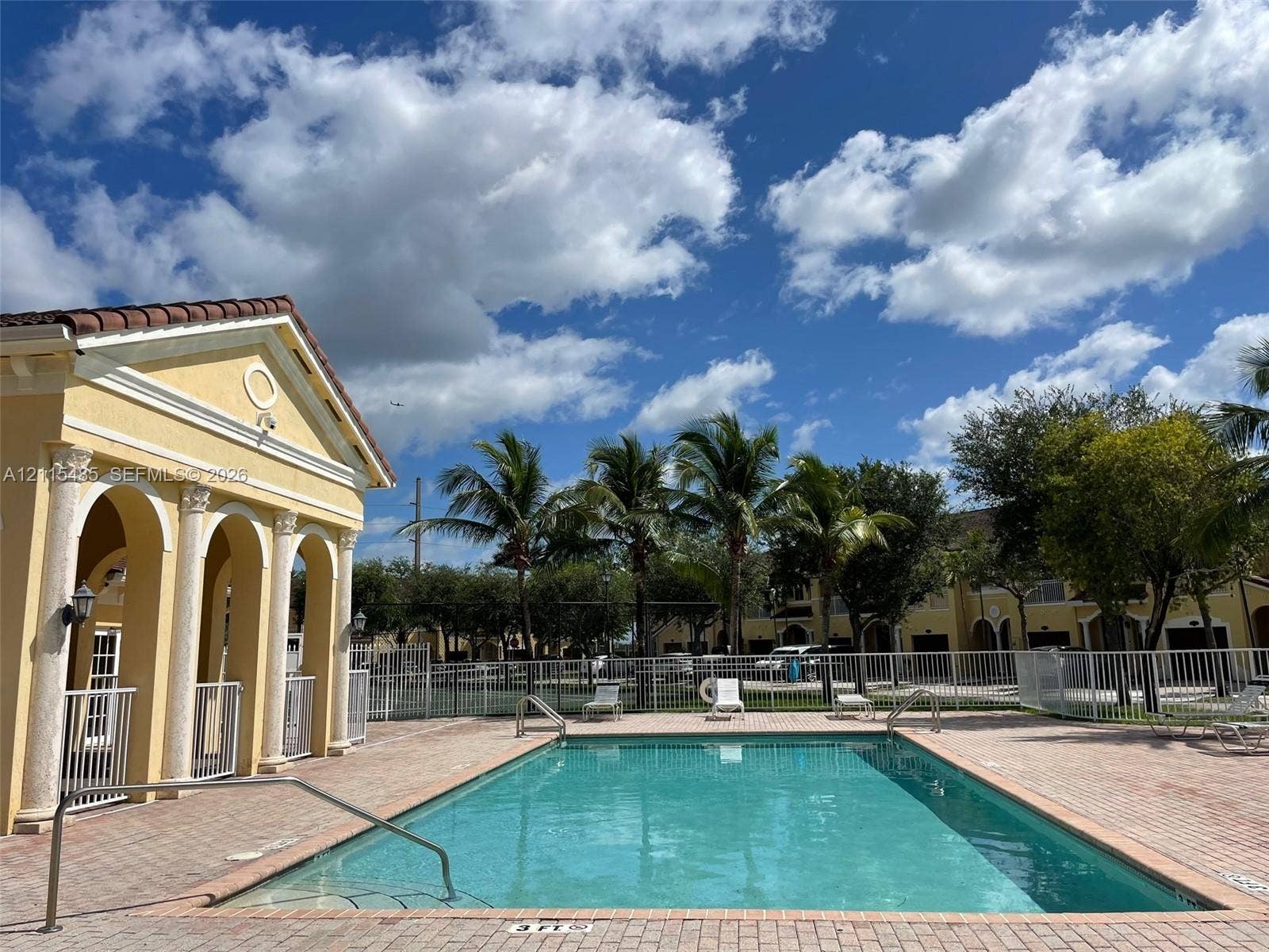 14973 SW 9th Terrace, Miami, Miami, FL 33194 Swimming pool with brick paver decking, enclosed by metal fencing, featuring a columned pavilion with arched entryways and tile roofing