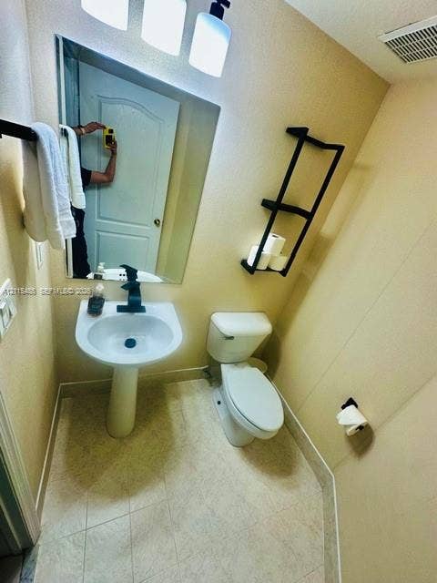 14973 SW 9th Terrace, Miami, Miami, FL 33194 Pedestal sink with matte black faucet, wall-mounted multi-tier shelving, large vanity mirror, matte black towel bar, and three-light vanity fixture