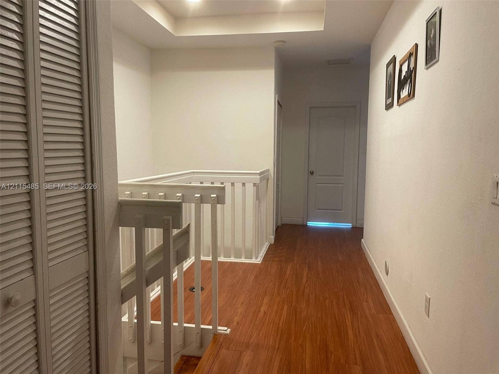 14973 SW 9th Terrace, Miami, Miami, FL 33194 Hallway featuring wood-finish flooring, white louvered-door closet, tray ceiling, and white wooden railing